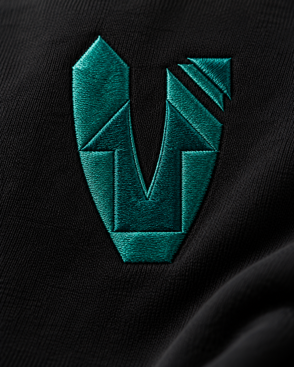 Close-up of the custom Elevate V embroidered in teal on black fabric